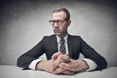 A man with a concerned look on his face sitting at a desk